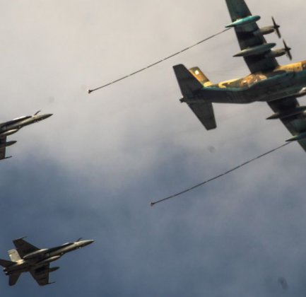 Three airplanes fly through the air, one big one leads and two smaller ones follow.