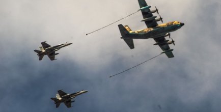 Three airplanes fly through the air, one big one leads and two smaller ones follow.