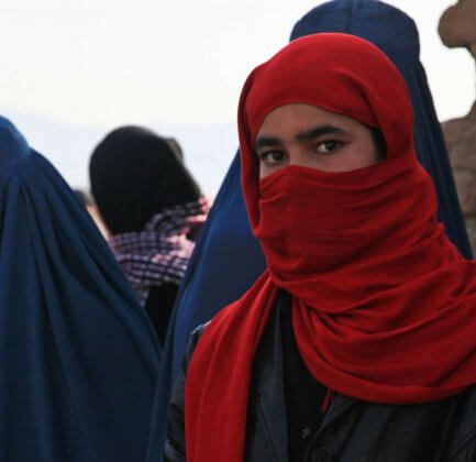 A row of women wearing a burka, one of which faces the camera