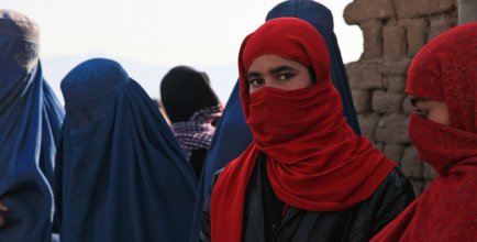A row of women wearing a burka, one of which faces the camera
