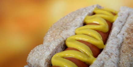 a hotdog with mustard on it in close up