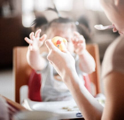 a woman feeding her baby and holding a toy duck