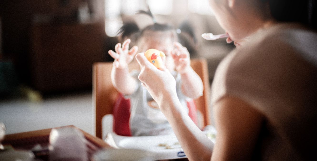 a woman feeding her baby and holding a toy duck
