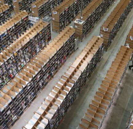 worker pulls itmes for an order among shelves lined with goods at an Amazon warehouse