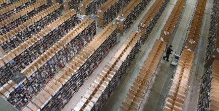worker pulls itmes for an order among shelves lined with goods at an Amazon warehouse
