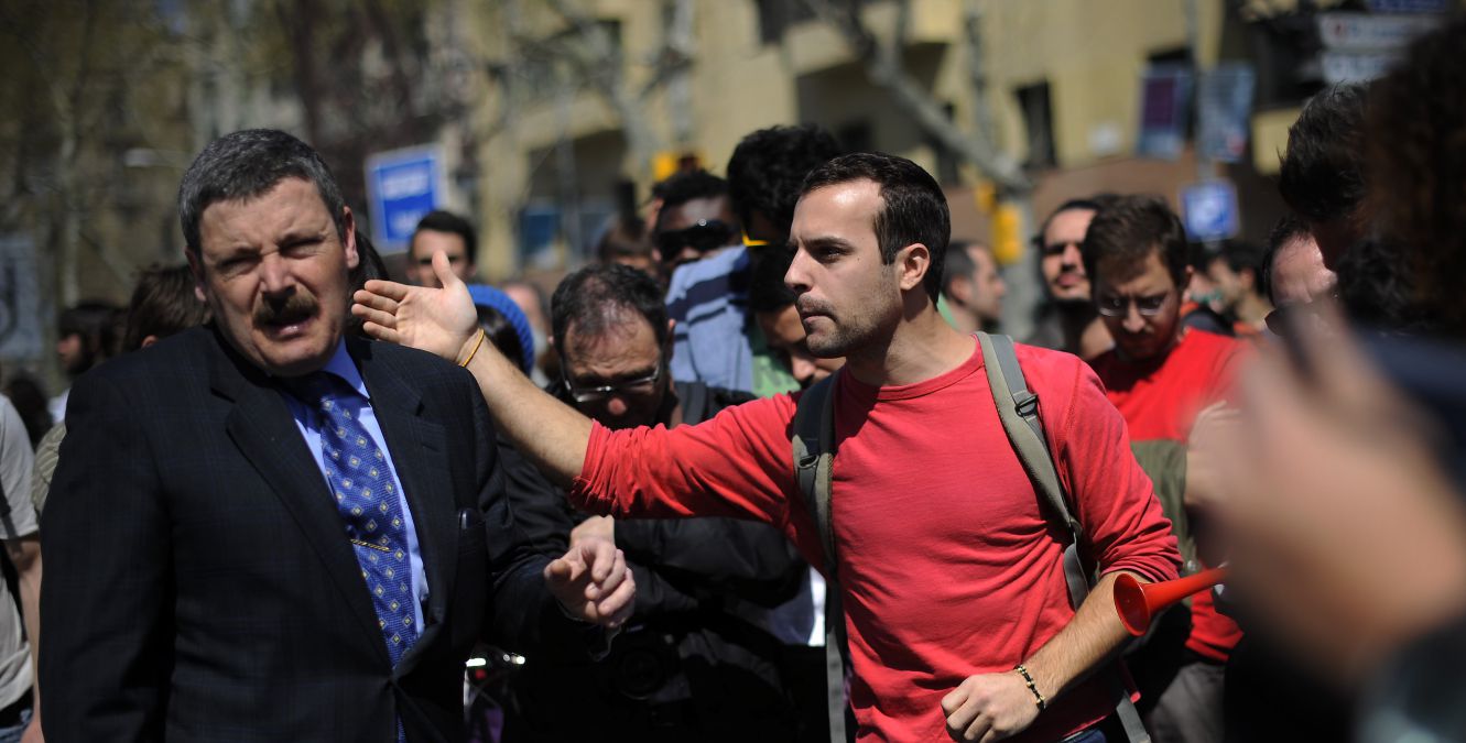 A man argues with demonstrators as they block a street