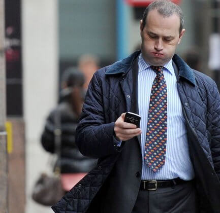 A man checking twitter on his mobile phone while walking.
