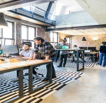Workers in a startup company open-plan office environment working together.